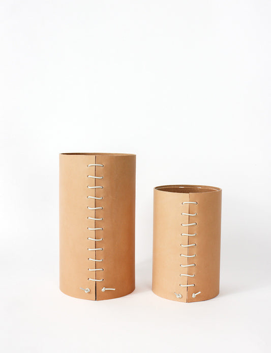 Two Leather Wrapped vases, one small, one medium. Cylindrical in shape, with a leather stitched detailing going down the middle where both leather ends meet.