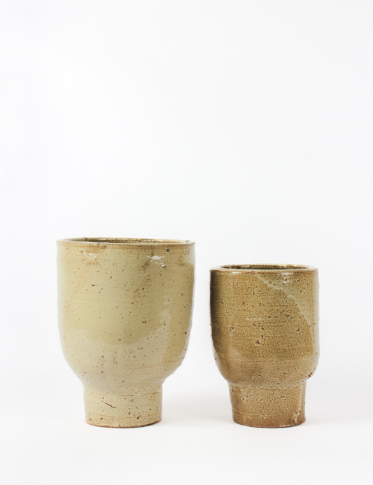 Luna indoor planter, with a beige slightly porous finish. Cylindrical body with pedestal bottom.