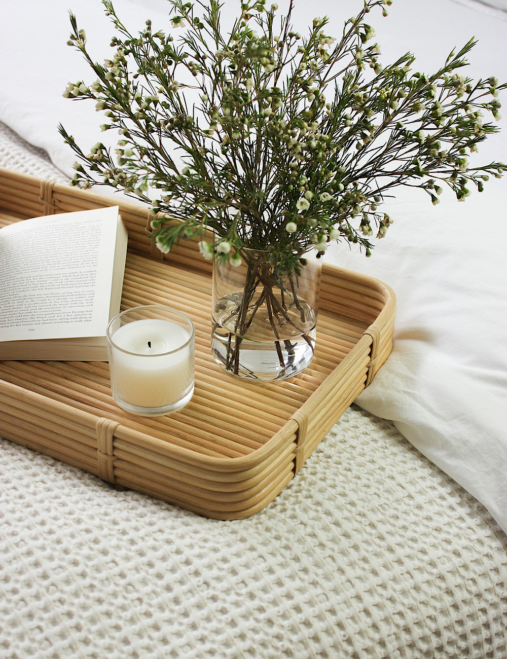 Styled shot of a rectangular tray close up. Styled with flowers, a candle and an open book.