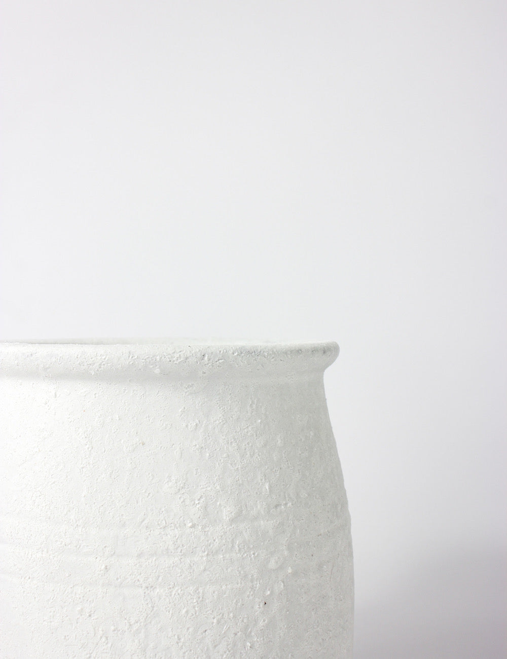 Close up of a white terracotta pot with a textured finish and bottle neck top opening.