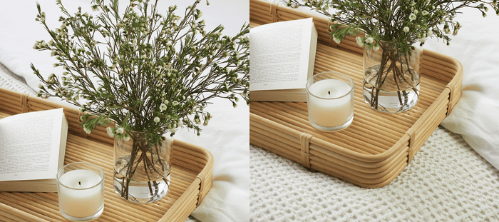 Bamboo tray on bed with vase of flowers, candle and open book. 