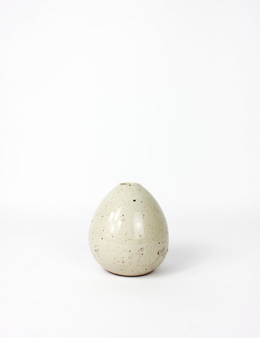 Small ceramic vase with an off white speckled finish and porous surface in some areas. Tear drop shape. 