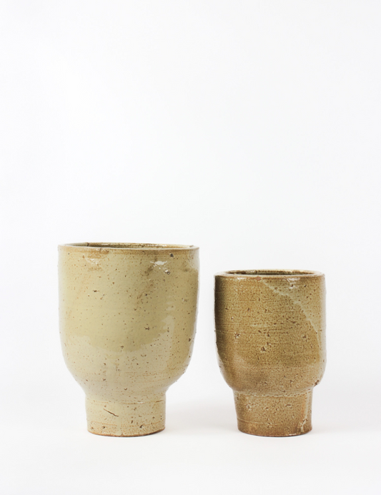 Luna indoor planter, with a beige slightly porous finish. Cylindrical body with pedestal bottom. 