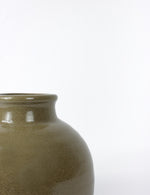 Close up shot of a dark green ceramic vase with a subtle speckled glaze finish.
