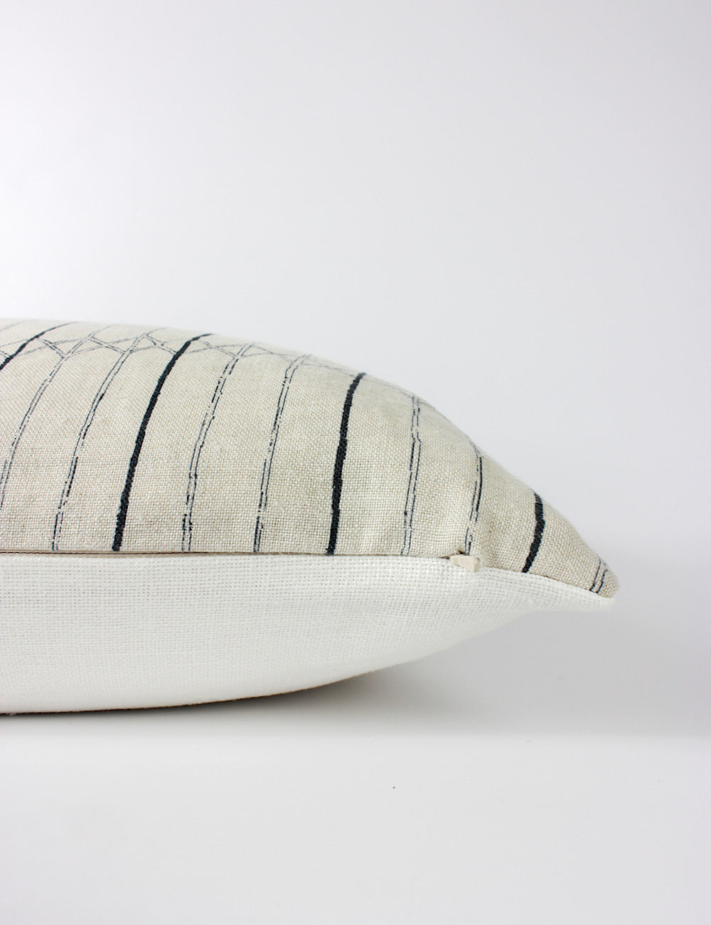 Side view of the Serena scatter cushion capturing its two-tone indigo striped pattern on the front and a plain off-white back and a hidden zip.