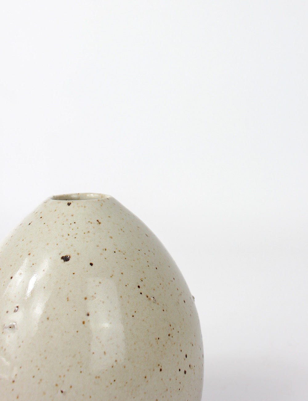 Close up of the Juno small ceramic vase with a speckled off white glaze and porous finish in some areas. 
