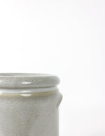 Close up shot of a blue / grey plant pot with a speckled glaze finish and cylindrical body. 