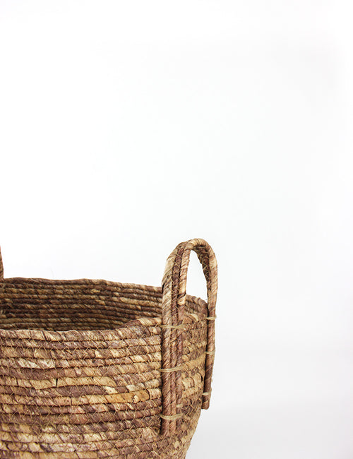 close up of a round storage basket capturing its woven texture and handle. 